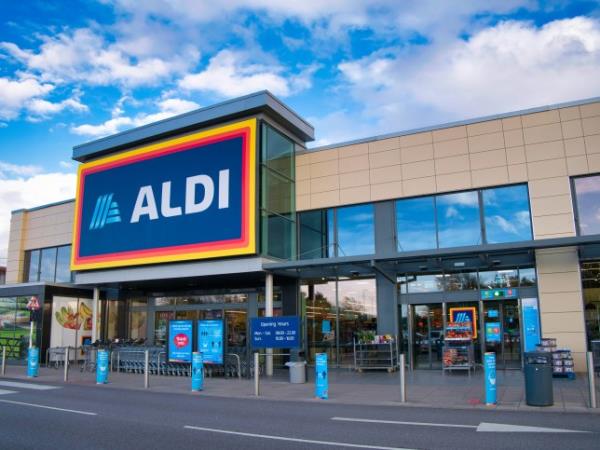 The fro<em></em>ntage and brand logo of a branch of German discount retailer Aldi, taken in a local retail park on Wirral, UK on a sunny afternoon