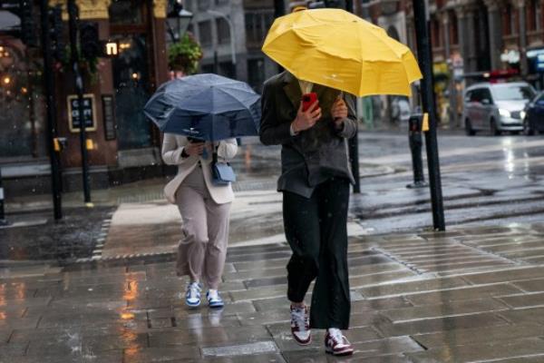 People walk through the rain and wet weather in Victoria, London