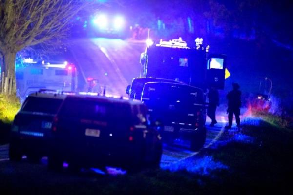 Law enforcement officers, right, stand near armored and tactical vehicles, center, near a property on Meadow Road, in Bowdoin, Maine, Thursday, Oct. 26, 2023. (AP Photo/Steven Senne)