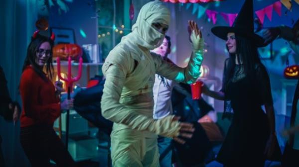 Halloween Costume Party: Old Skinny and Bandaged Mummy Dances. In the Background Zombie, Death, Witch and She Devil Have Fun in a Mo<em></em>nster Party Decorated Room