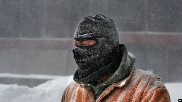 FILE - A man wears a ski mask to shield his face from the wind-driven snow while shoveling a sidewalk, Jan 27, 2015, in downtown Portland, Maine. 